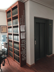 Otra estanter&iacute;a de la Sala de Consulta del Archivo y la Biblioteca Auxiliar de cuyo costado cuelgan los modelos de solicitud de libros, revistas y documentos. 